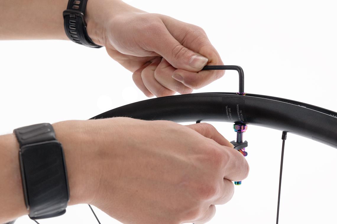 Wentyl montuje się od wewnątrz obręczy, gumowa podstawka uszczelnia połączenie. Klucz imbusowy do dokręcenia nakrętki od zewnątrz – nie za mocno, żeby nie uszkodzić taśmy.