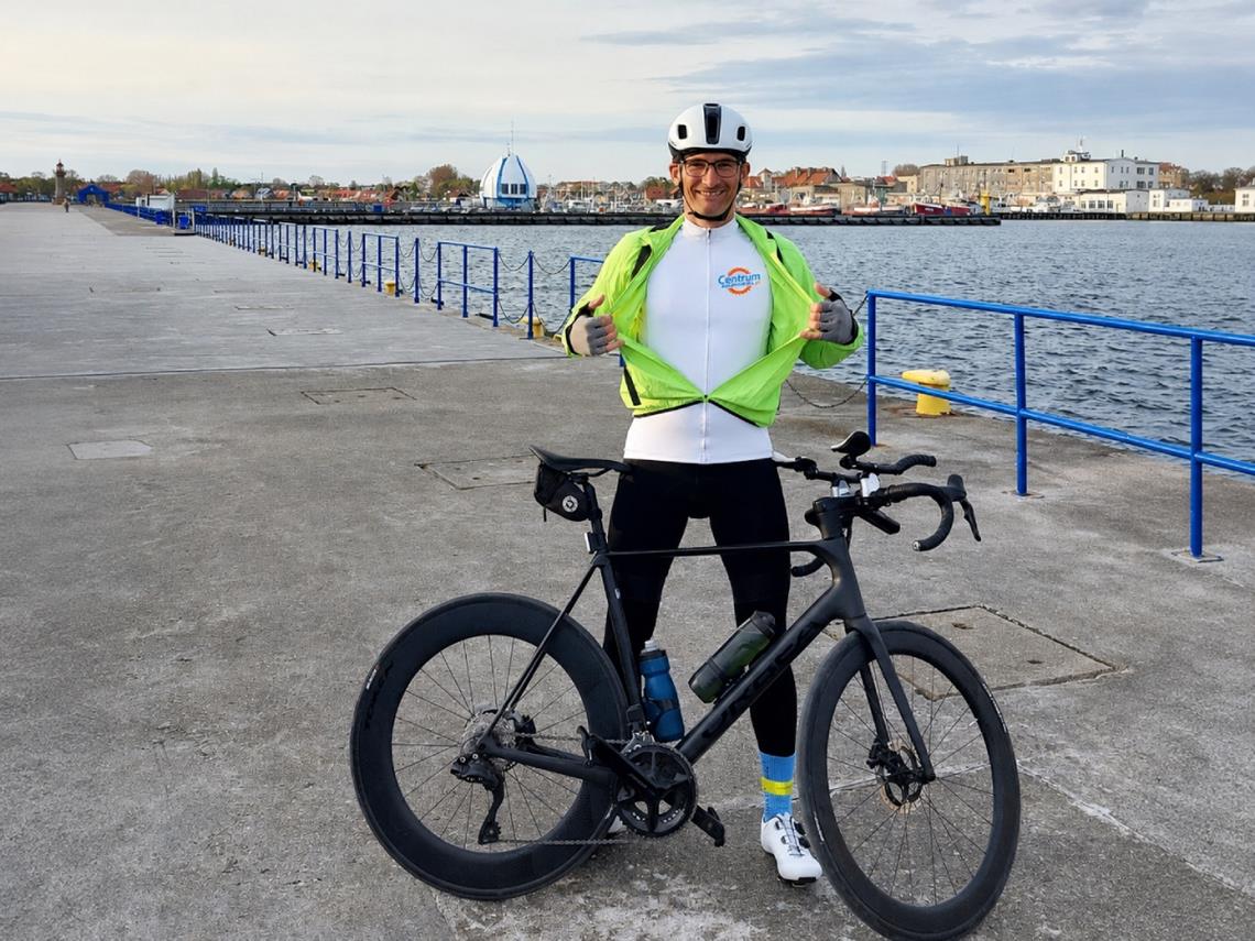Jacek Kwiatkowski w koszulce Centrumrowerowe.pl, obok stoi rower