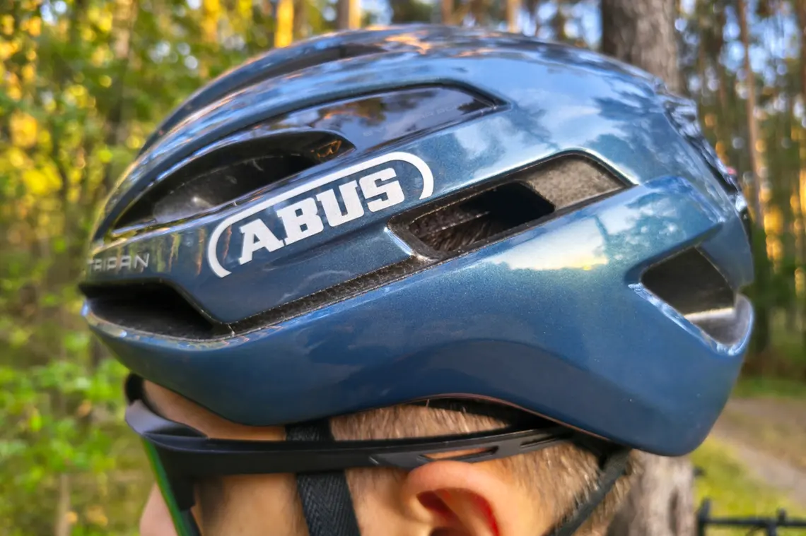 Kask ABUS Taipan założony na głowie rowerzysty będącego w lesie.