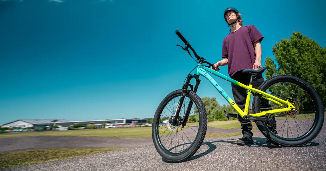 Rowerzysta dirtowy stoi na pumptracku prezentując rower marki Oxfeld.